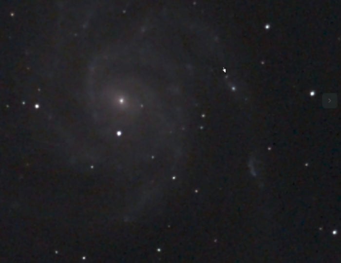 The photo of the Pinwheel Galaxy and the supernova taken May 18 by Alex Filippenko, more than 11 hours before it was discovered. Filippenko, who snapped the photo with his Unistellar eVscope, only noticed the supernova after the discovery of SN 2023ixf was announced on May 19. The supernova is the faint object marked with a small arrow, located in the outer reaches of the galaxy.