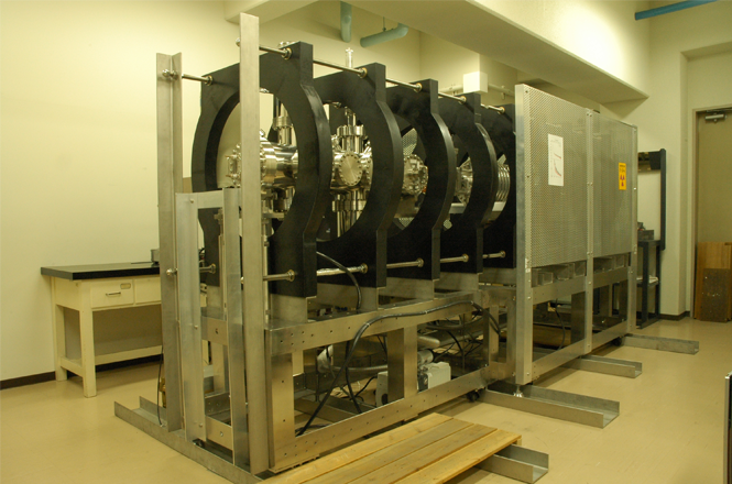 The slow positron beam apparatus used in the present study. The apparatus is installed at Tokyo University of Science (TUS). Positrons emitted from a 22Na source capsule by β+ decay are moderated using a moderator made of tungsten mesh, extracted into vacuum, and transported to a sample using a static magnetic field. The research group at TUS has achieved various results using this apparatus, including experiments on the emission of positronium neutral atoms or positronium negative ions from solid surfaces. 