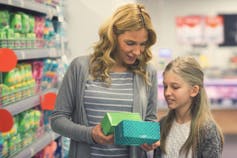 A mother and daughter compare boxes of pads in a store.