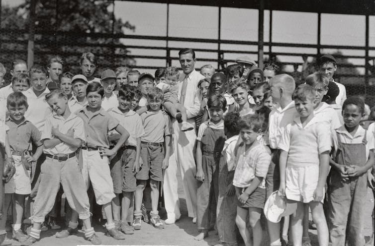 Hank Greenberg posing for a photo with dozens of youngsters.