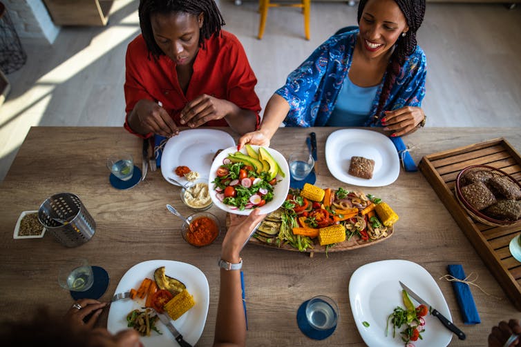 view from above of several women sharing a variety of healthy foods at a wooden table