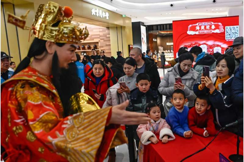 A humanoid robot in traditional Chinese costume answers questions at an AI-themed temple fair in Beijing