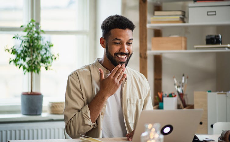 Young man with laptop signing on a video call