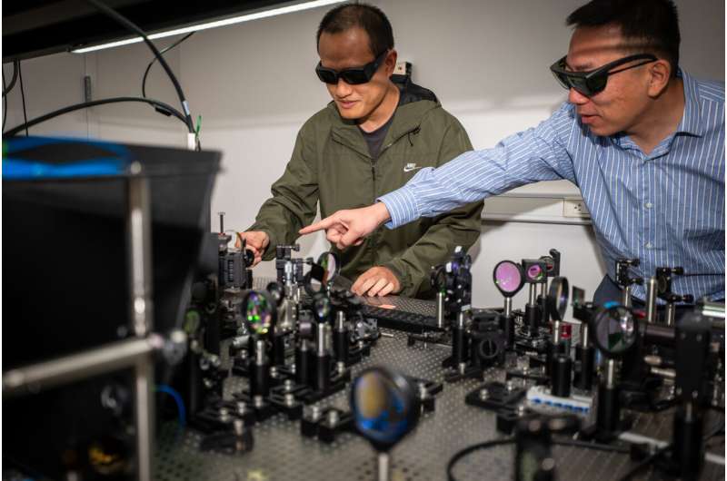 Postdoctoral fellow Tianwei Wu (left) and Professor Liang Feng (right) in the lab, demonstrating some of the apparatus used to develop the new, light-powered chip. Credit: Sylvia Zhang. Penn engineers first to train AI at lightspeed