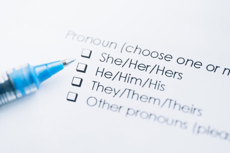 A blue pen next to a list of personal pronouns on a form on white paper.
