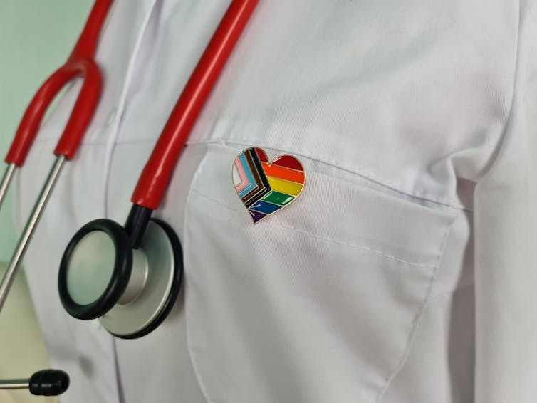 Silhouette of doctor in white coat with stethoscope and LGBTQ+ pin on pocket