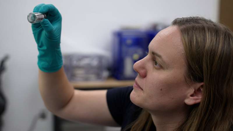 Jessica Barnes examines a vial containing sample particles at the Kuiper-Arizona Laboratory for Astromaterials Analysis, located at the University of Arizona. Credit: Chris Richards, University of Arizona Asteroid Bennu is a time capsule of materials bearing witness to its origin and transformation over billions of years