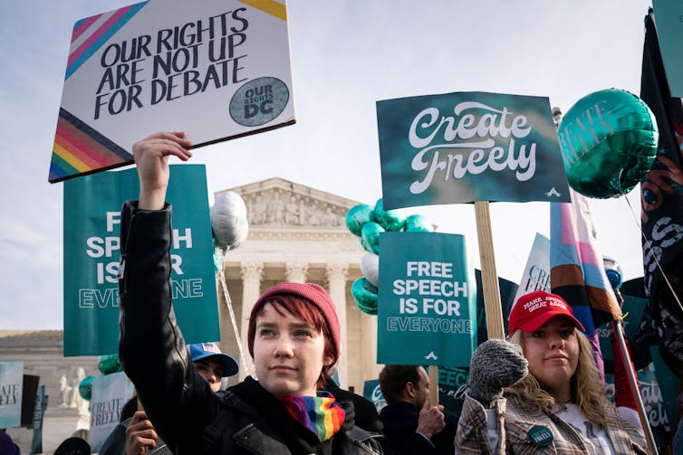 People with protest and support signs stand outside of the U.S. Supreme Court building.