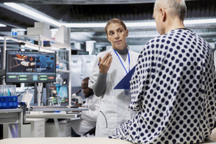 A pharmacologist talking to a patient in a research laboratory.