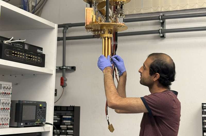 Ph.D. student Vivek Wadhia sets up the dilution fridge inside which the quantum clock experiment was carried out. Credit: Martyna Sienkiewicz. Reading a quantum clock costs more energy than running it, study finds