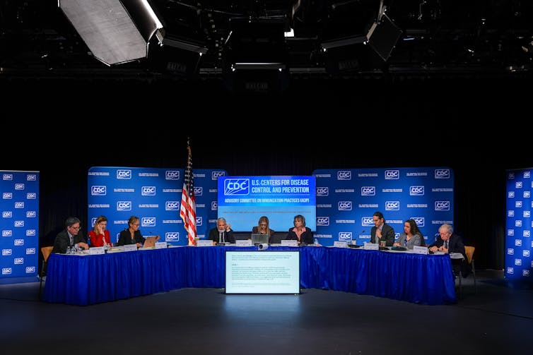 Members of the CDC Advisory Committee on Immunization Practices sitting at a long table.