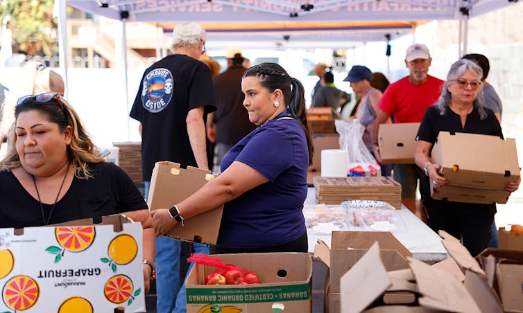 People carrying boxes of food under a tent
