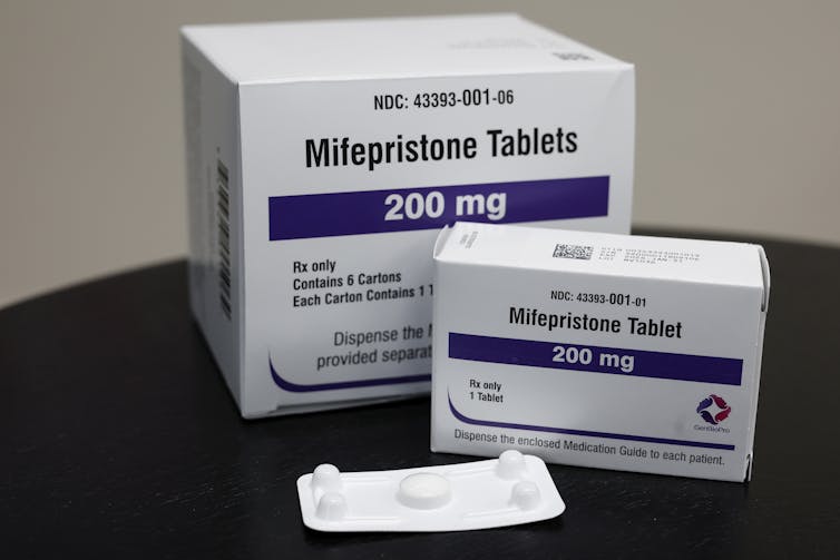 Packages of mifepristone tablets are displayed.