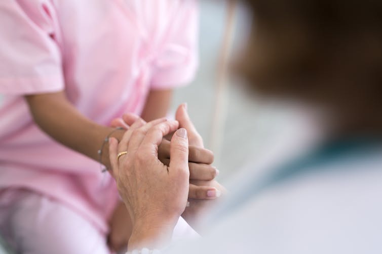 A person holds another person's hand in a health clinic.