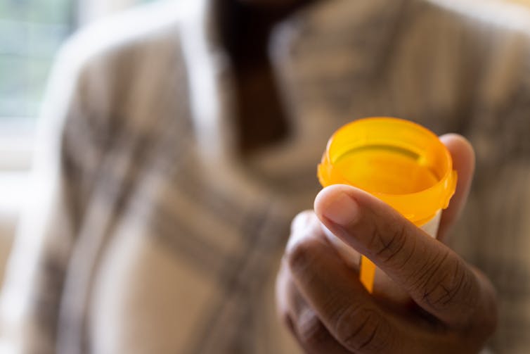 Close-up of person holding an orange pill bottle