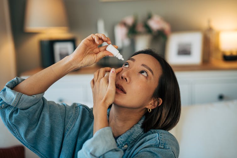 Young adult woman applying eye drops.