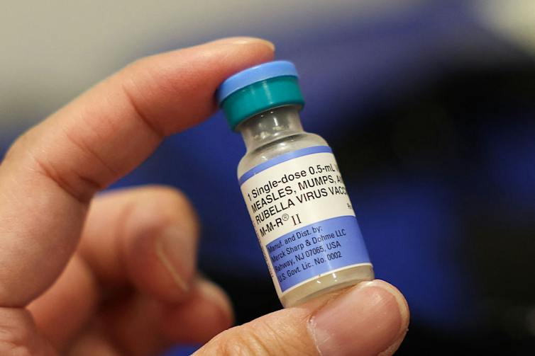 A small vial is held between a person's thumb and forefinger.